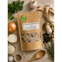Load image into Gallery viewer, A stand-up pouch of Pure Kitchin Mushroom Risotto Mix surrounded by cooking ingredients including mushrooms, garlic, onion, parsley, thyme, salt, peppercorns, and a wooden spoon on a beige stone surface.