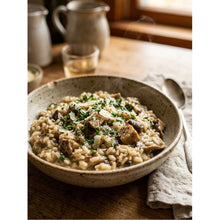 Load image into Gallery viewer, A ceramic speckled bowl filled with creamy mushroom risotto, garnished with fresh parsley and cheese shavings, set on a rustic wooden table with a spoon and napkin.
